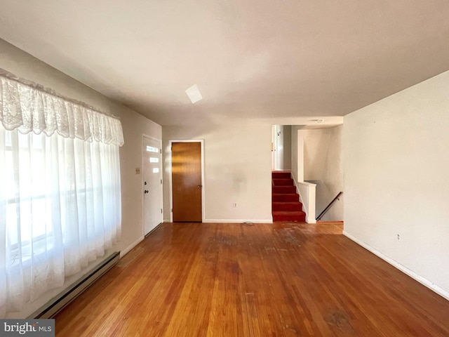 empty room featuring wood-type flooring and a baseboard radiator