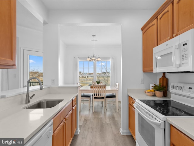 kitchen featuring light countertops, white appliances, a sink, and pendant lighting