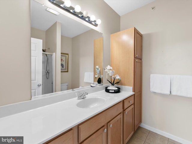 bathroom featuring baseboards, toilet, a shower with door, tile patterned flooring, and vanity