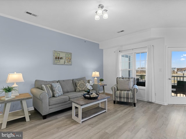 living room featuring light wood finished floors, visible vents, and crown molding