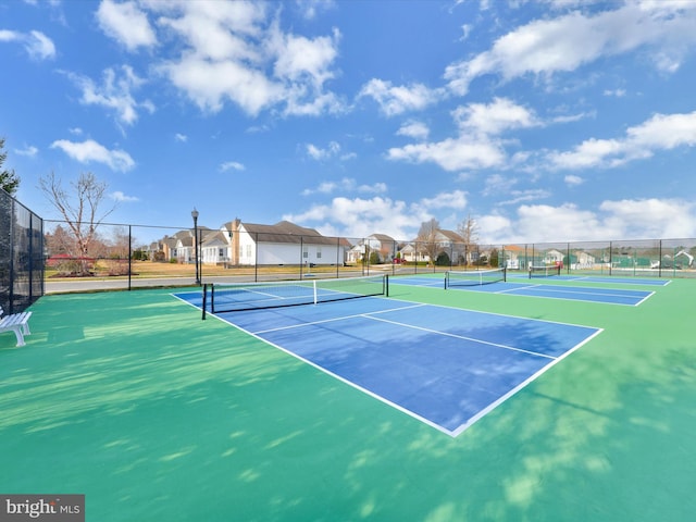 view of tennis court featuring fence and a residential view