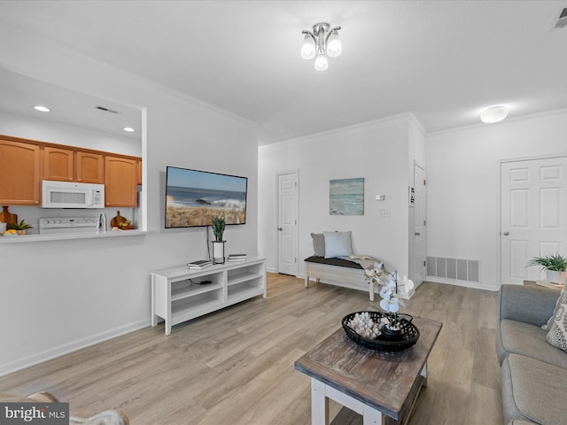 living room featuring light wood-style floors, baseboards, visible vents, and crown molding