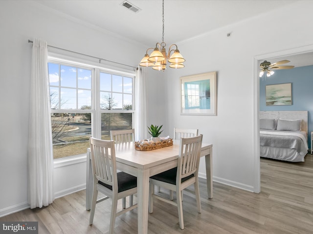 dining room with baseboards, light wood-type flooring, visible vents, and crown molding