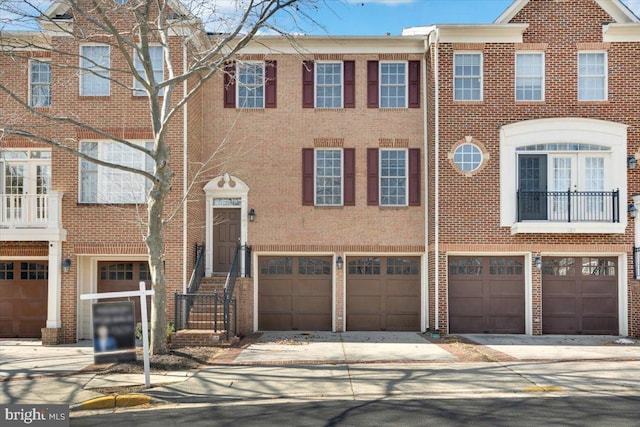 multi unit property with a garage, driveway, and brick siding