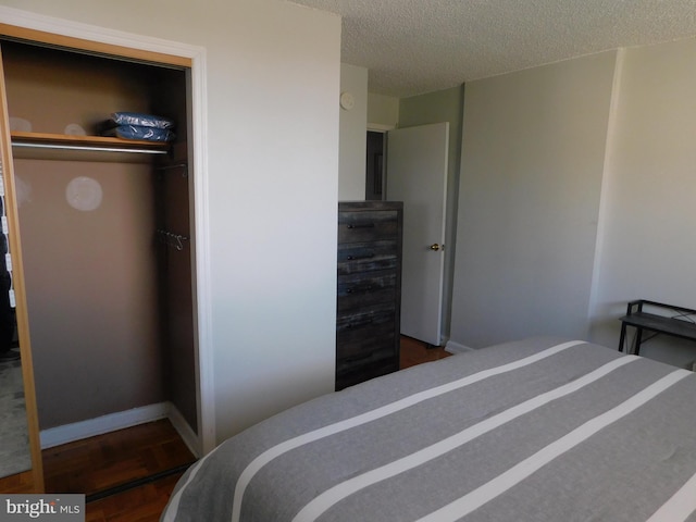 bedroom with a closet, dark hardwood / wood-style flooring, and a textured ceiling