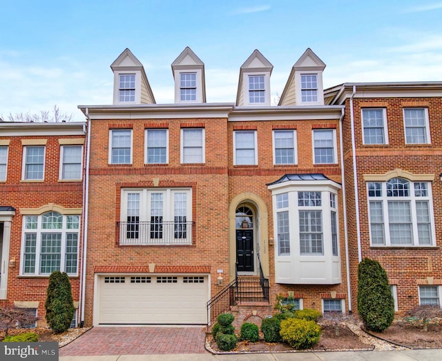 view of property with a garage, decorative driveway, and brick siding