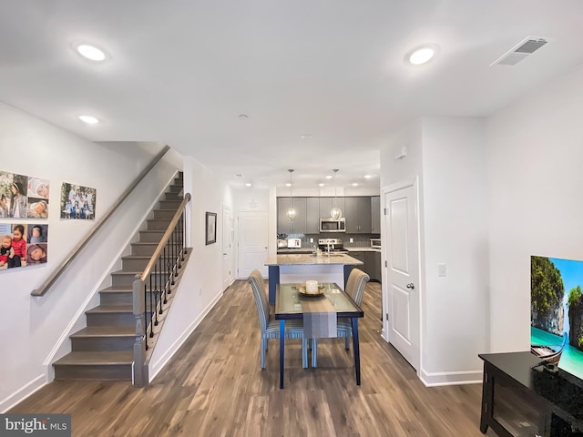 dining space featuring dark wood-style flooring, recessed lighting, visible vents, baseboards, and stairs