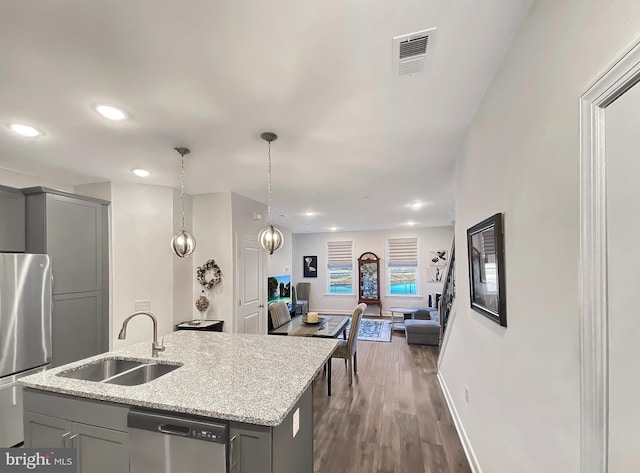 kitchen featuring visible vents, open floor plan, gray cabinets, stainless steel appliances, and a sink