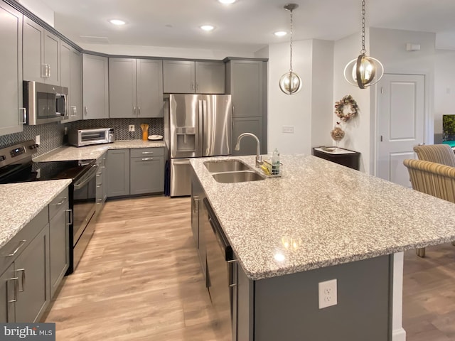 kitchen featuring appliances with stainless steel finishes, light wood-style floors, backsplash, and a sink