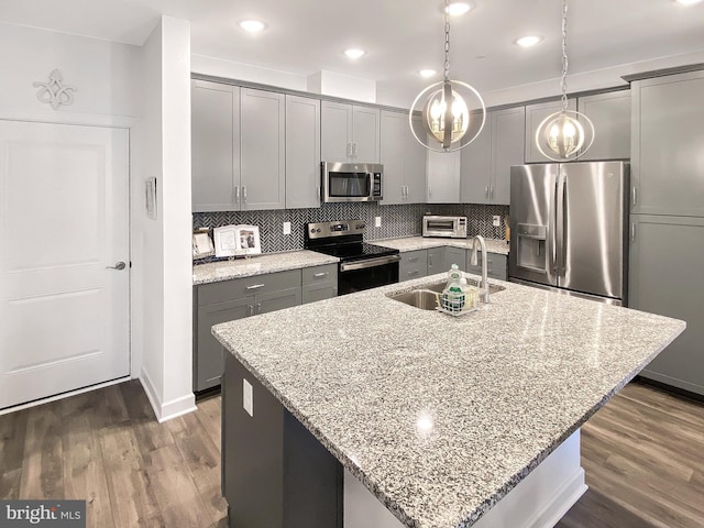 kitchen with appliances with stainless steel finishes, gray cabinets, a sink, and decorative backsplash