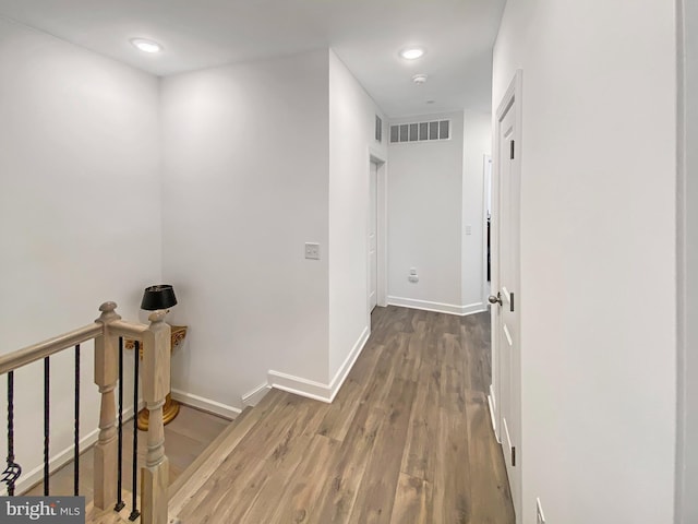 corridor with recessed lighting, wood finished floors, an upstairs landing, visible vents, and baseboards