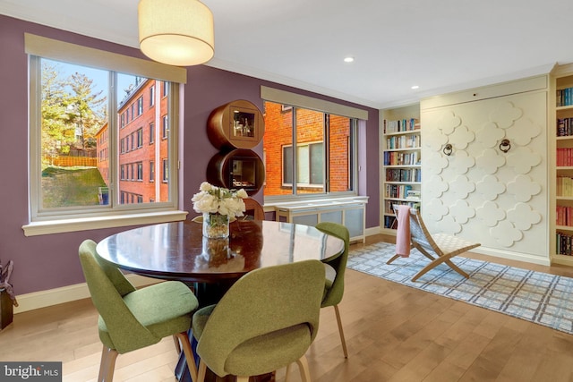 dining room featuring built in features, ornamental molding, and light hardwood / wood-style flooring