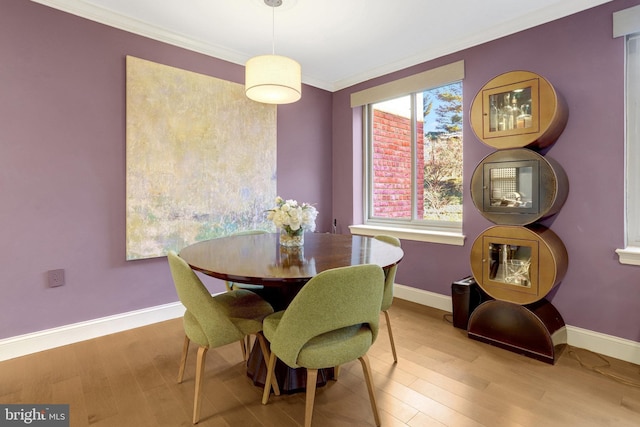 dining space featuring light wood-type flooring and crown molding