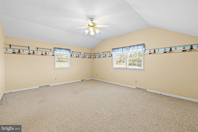 carpeted spare room featuring vaulted ceiling and ceiling fan