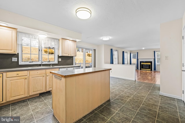 kitchen with white dishwasher, sink, light brown cabinetry, and a center island