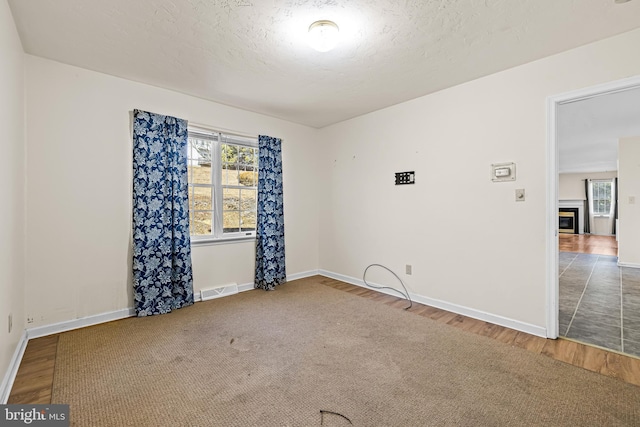 empty room featuring a textured ceiling, hardwood / wood-style floors, and a healthy amount of sunlight