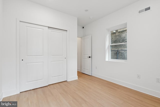 unfurnished bedroom with light wood-type flooring and a closet