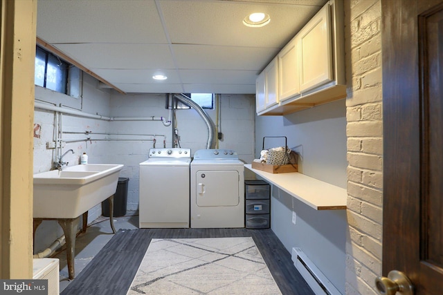 clothes washing area with sink, dark hardwood / wood-style flooring, a baseboard heating unit, cabinets, and separate washer and dryer