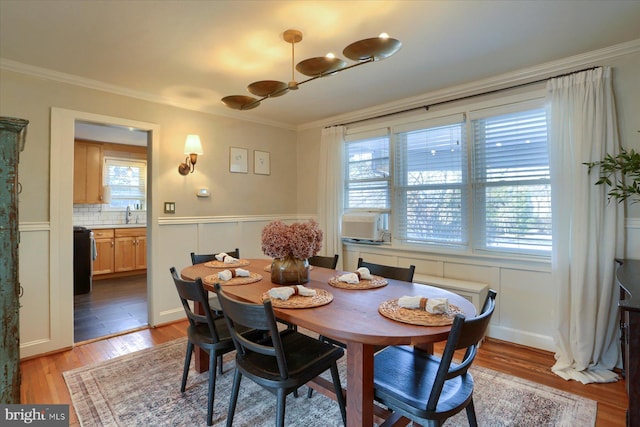 dining area with crown molding, sink, light wood-type flooring, and a wealth of natural light