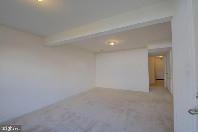 spare room featuring beamed ceiling and light carpet