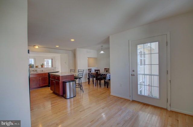 kitchen with a kitchen breakfast bar, a kitchen island, light hardwood / wood-style floors, and sink