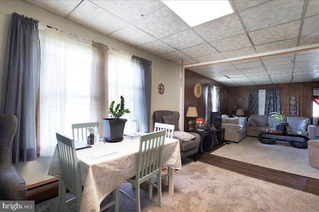 dining room with a paneled ceiling, hardwood / wood-style floors, and wood walls