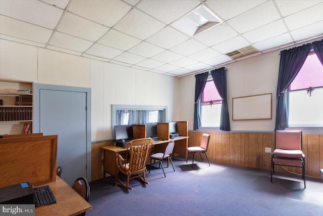 carpeted office with a drop ceiling and wood walls