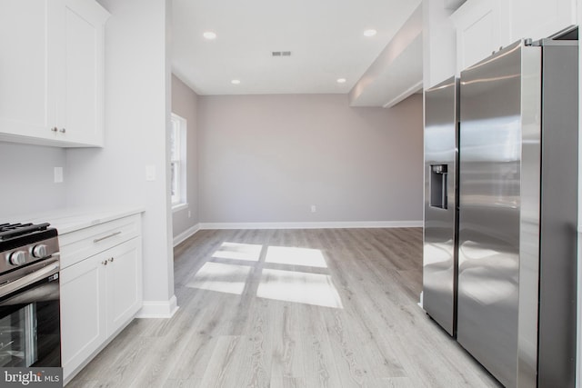 kitchen with appliances with stainless steel finishes, visible vents, white cabinets, and light wood-style flooring