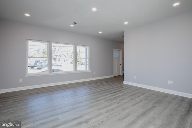 spare room with recessed lighting, wood finished floors, visible vents, and baseboards