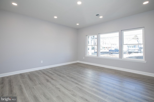 spare room with recessed lighting, wood finished floors, visible vents, and baseboards