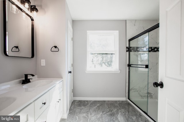 full bath featuring double vanity, marble finish floor, a marble finish shower, and a sink