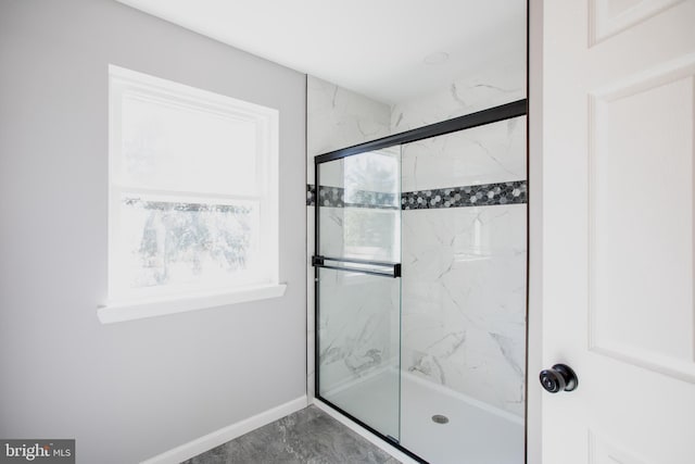 full bath featuring a marble finish shower and baseboards