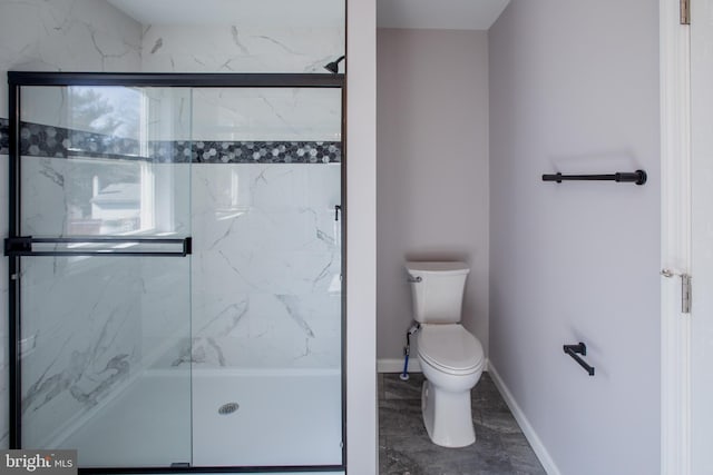 bathroom with a marble finish shower, toilet, and baseboards