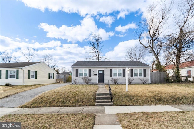 view of front of house with aphalt driveway, a front lawn, and fence