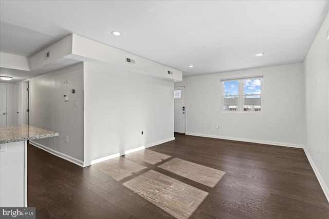 unfurnished living room with dark wood-type flooring, recessed lighting, visible vents, and baseboards