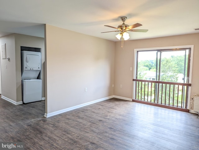 spare room featuring stacked washer / dryer, dark wood-type flooring, and ceiling fan