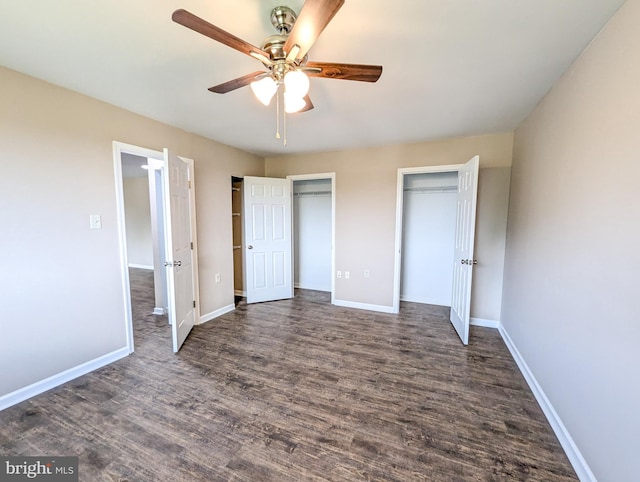 unfurnished bedroom with multiple closets, dark hardwood / wood-style floors, and ceiling fan