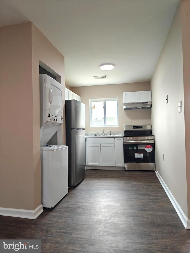 kitchen with stainless steel appliances, stacked washer / dryer, white cabinets, and dark hardwood / wood-style flooring