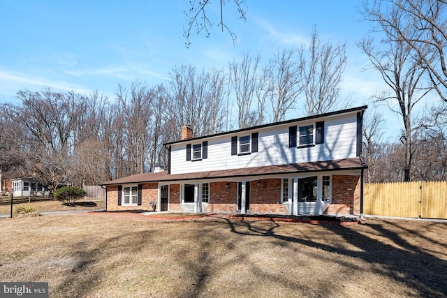 view of front of home featuring a chimney, fence, a front lawn, a porch, and brick siding