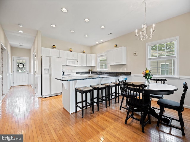 kitchen featuring dark countertops, white appliances, white cabinets, and light wood-style floors