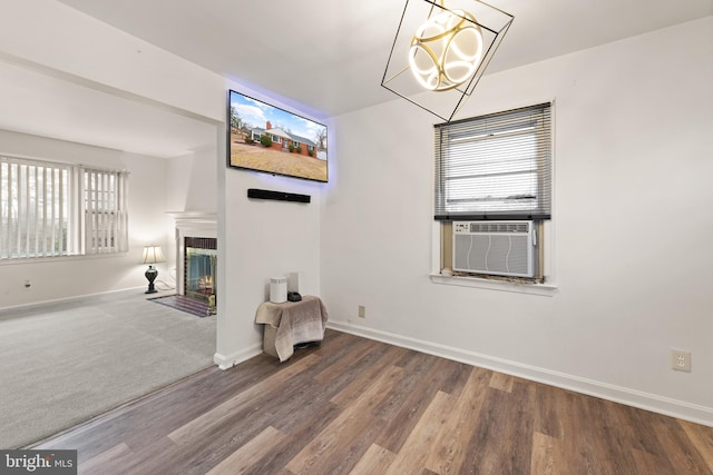 interior space with a fireplace with flush hearth, cooling unit, baseboards, and wood finished floors