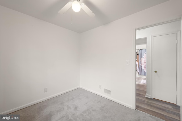 empty room with a ceiling fan, carpet flooring, visible vents, and baseboards