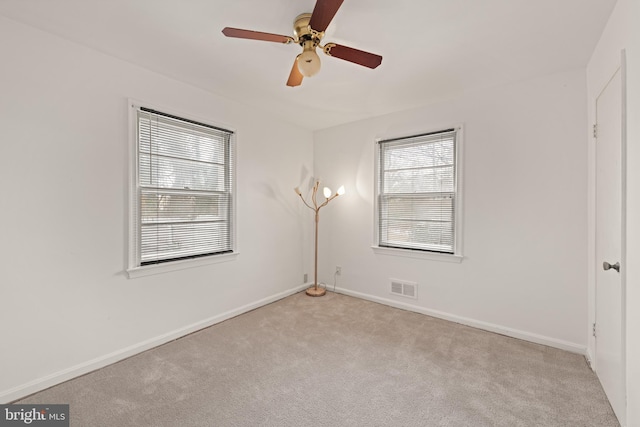 spare room featuring light carpet, ceiling fan, visible vents, and baseboards