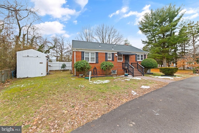 view of front of property with brick siding, fence, a shed, an outdoor structure, and a front lawn