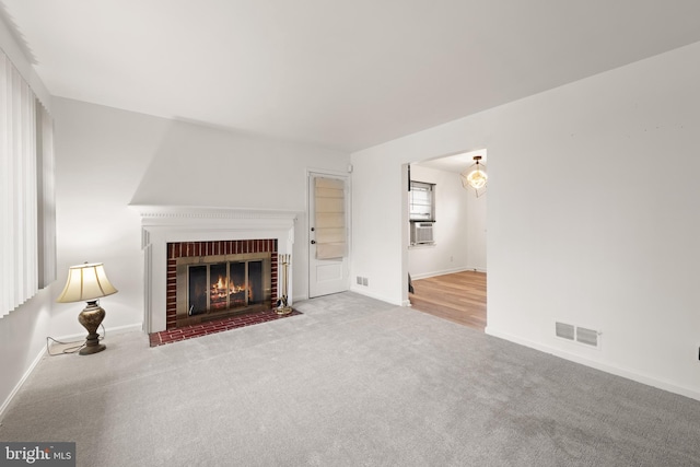 unfurnished living room with visible vents, a fireplace, light carpet, and baseboards