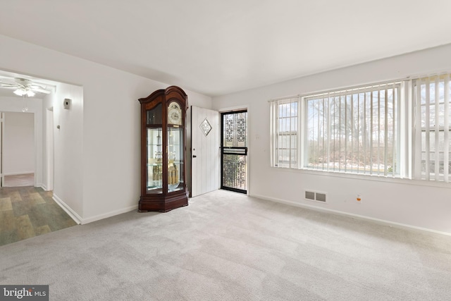 spare room with light carpet, baseboards, visible vents, and a ceiling fan