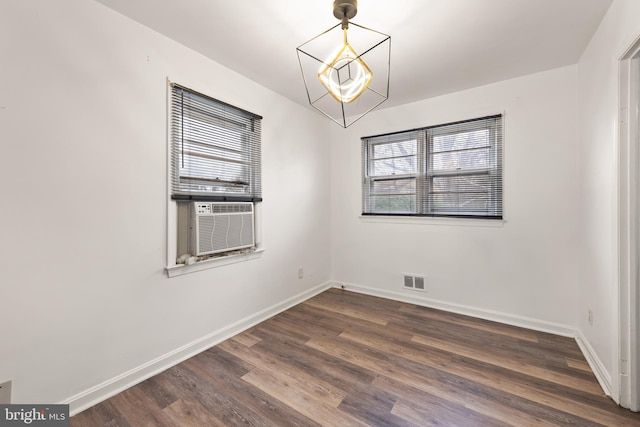 empty room featuring visible vents, baseboards, dark wood-style flooring, cooling unit, and a chandelier