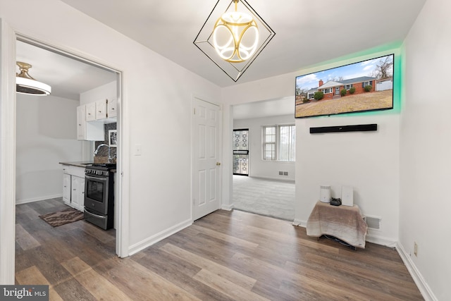 hallway featuring visible vents, a notable chandelier, baseboards, and wood finished floors