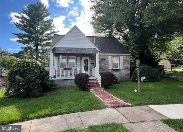 bungalow featuring stone siding, covered porch, a shingled roof, and a front lawn