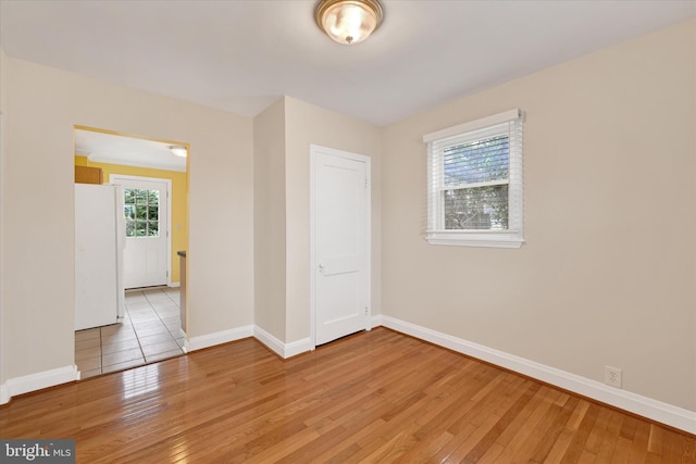 spare room with baseboards and light wood finished floors